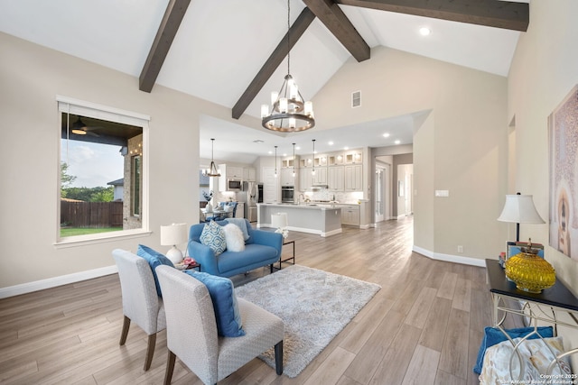 living room with an inviting chandelier, visible vents, beam ceiling, baseboards, and light wood-style flooring