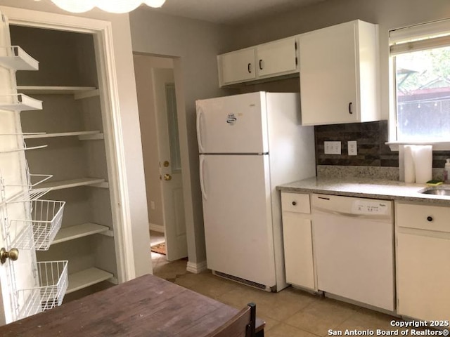 kitchen featuring backsplash, light tile patterned floors, light countertops, white cabinets, and white appliances