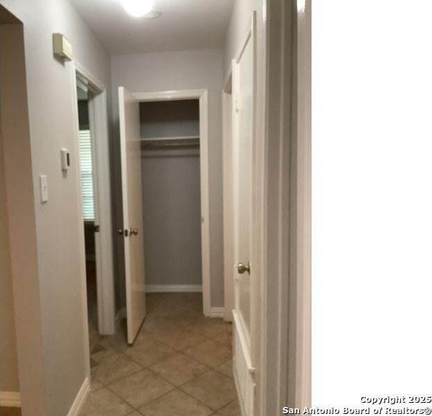 corridor featuring baseboards and light tile patterned flooring