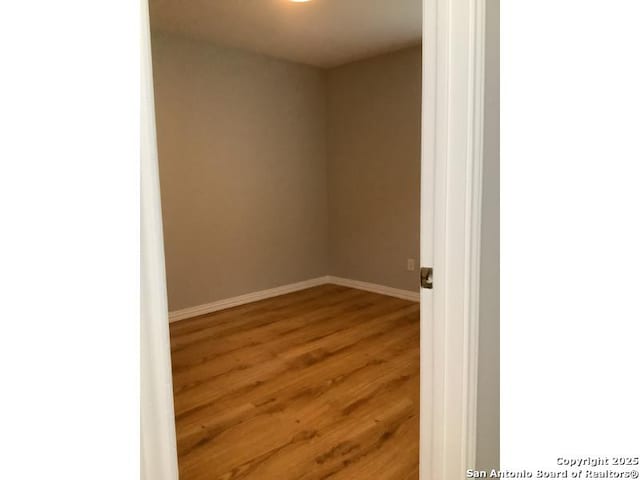 spare room with baseboards and wood finished floors