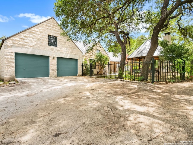 exterior space with fence, stone siding, a standing seam roof, an outdoor structure, and metal roof
