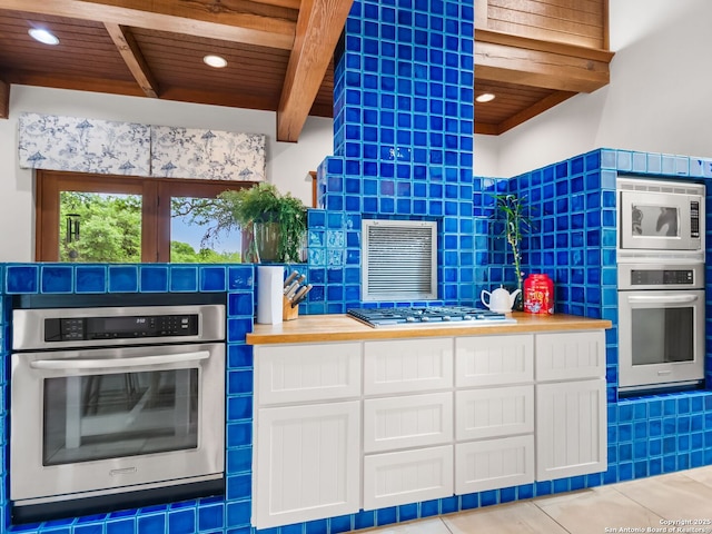 kitchen featuring white cabinets, stainless steel appliances, beamed ceiling, and wooden ceiling