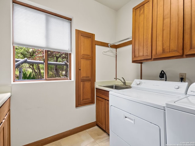 laundry area featuring washing machine and clothes dryer, cabinet space, a sink, baseboards, and light tile patterned flooring