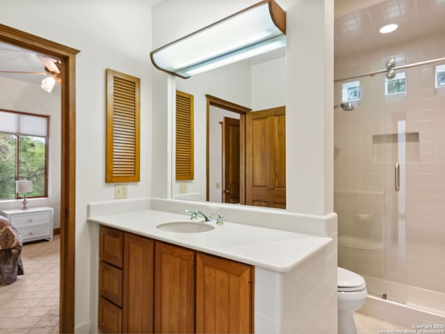 bathroom featuring toilet, ceiling fan, a shower stall, and vanity
