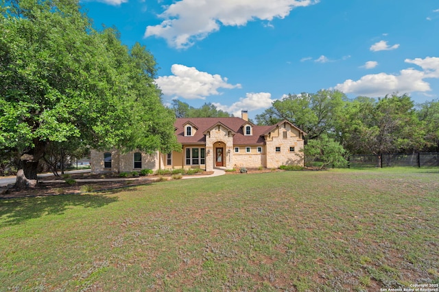 view of front of property featuring fence, a chimney, a front yard, and stone siding