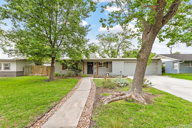 ranch-style house featuring an attached garage, fence, a front yard, and concrete driveway