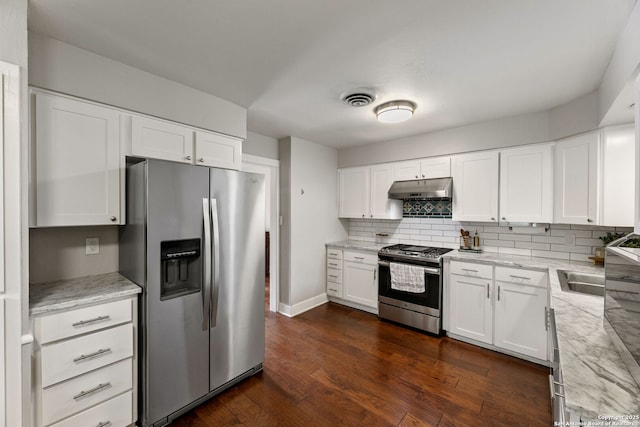 kitchen with dark wood-style flooring, light stone countertops, stainless steel appliances, tasteful backsplash, and under cabinet range hood