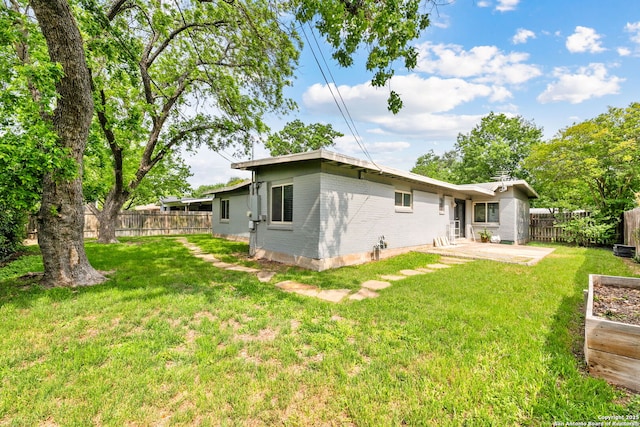 rear view of house with a fenced backyard, a lawn, a patio area, and brick siding