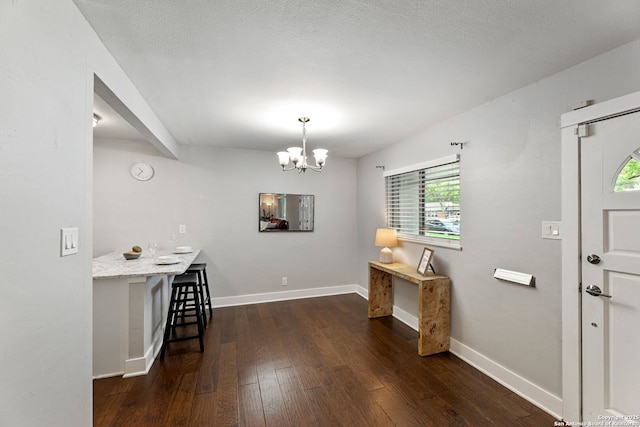 entrance foyer featuring an inviting chandelier, baseboards, and dark wood-style floors