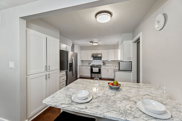 kitchen with under cabinet range hood, stainless steel appliances, white cabinets, and light stone countertops