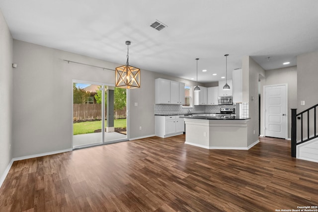 kitchen featuring dark wood-style flooring, dark countertops, stainless steel appliances, decorative backsplash, and visible vents