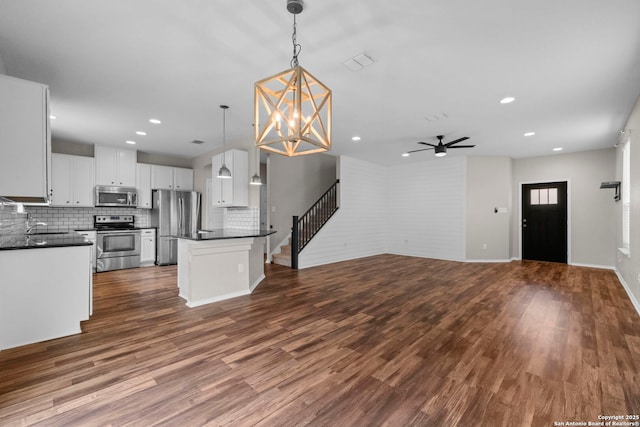 kitchen featuring decorative backsplash, ceiling fan with notable chandelier, dark countertops, recessed lighting, and appliances with stainless steel finishes
