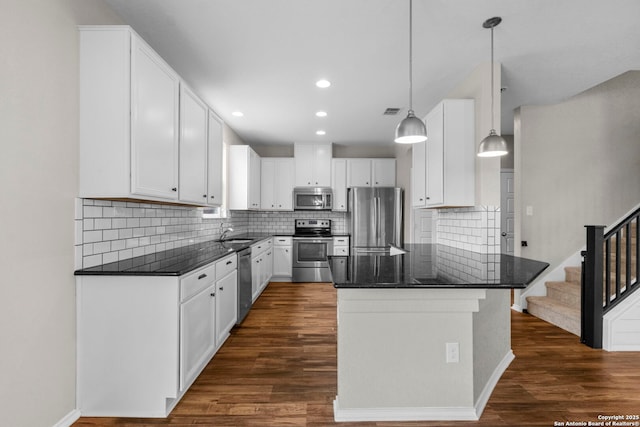 kitchen with appliances with stainless steel finishes, tasteful backsplash, dark wood-style flooring, and dark stone countertops