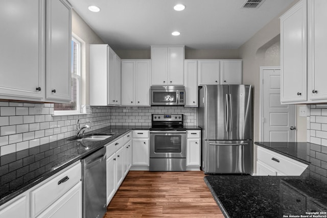 kitchen with white cabinetry, appliances with stainless steel finishes, decorative backsplash, and a sink