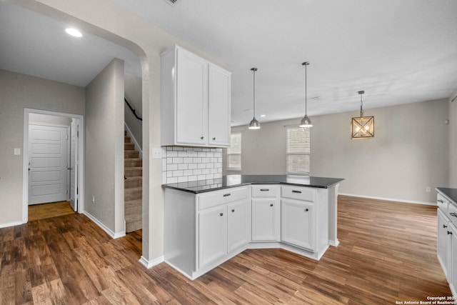 kitchen featuring dark countertops, white cabinets, a peninsula, and wood finished floors