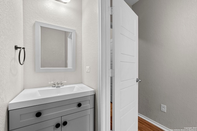 bathroom with vanity, baseboards, and wood finished floors