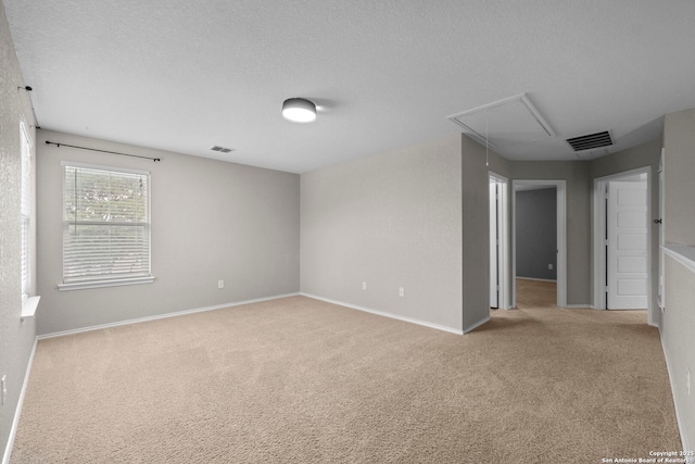 carpeted empty room with visible vents, attic access, and baseboards
