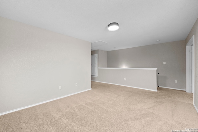 carpeted empty room with baseboards and attic access