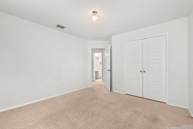 unfurnished bedroom with baseboards, visible vents, a closet, and light colored carpet