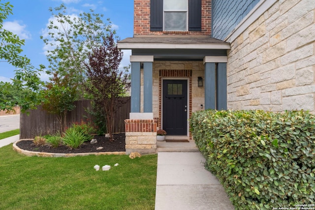 doorway to property featuring fence and stone siding