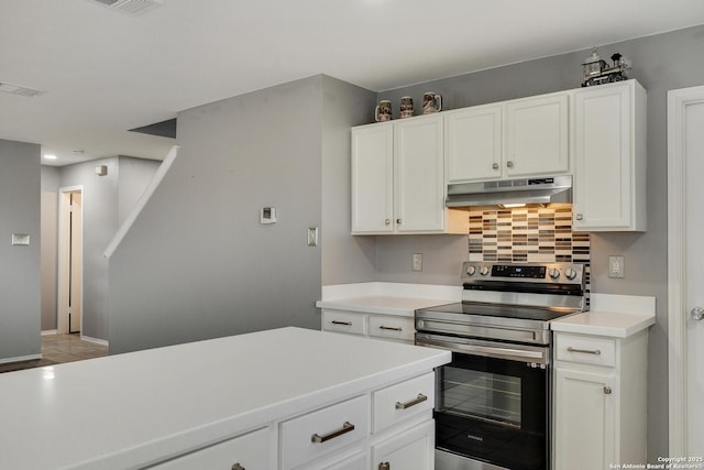 kitchen with backsplash, light countertops, white cabinets, electric stove, and under cabinet range hood