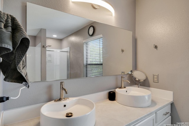 full bath featuring a sink, a textured wall, and a shower stall