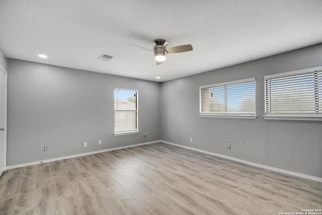 empty room featuring visible vents, light wood-style floors, ceiling fan, and baseboards
