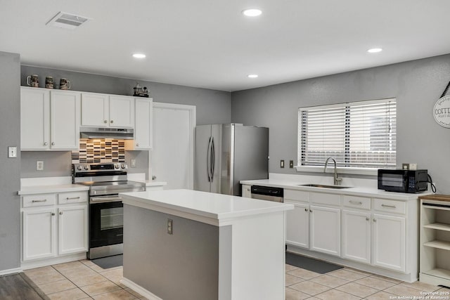 kitchen featuring appliances with stainless steel finishes, a sink, light countertops, under cabinet range hood, and visible vents