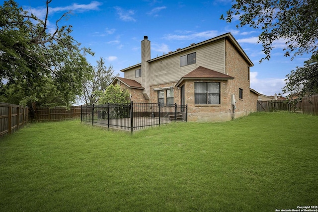 back of property featuring a lawn, a fenced backyard, brick siding, and a chimney
