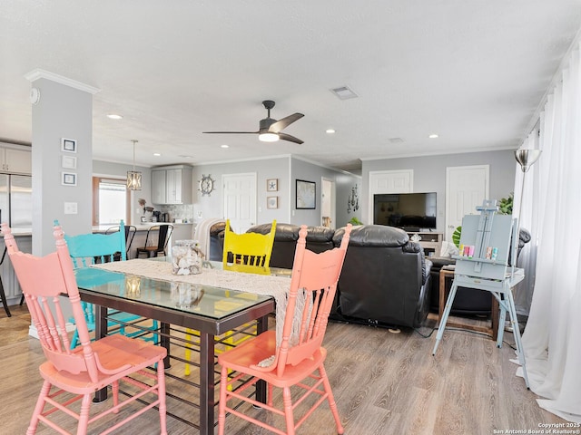 dining space featuring light wood-style floors, a ceiling fan, recessed lighting, and ornamental molding