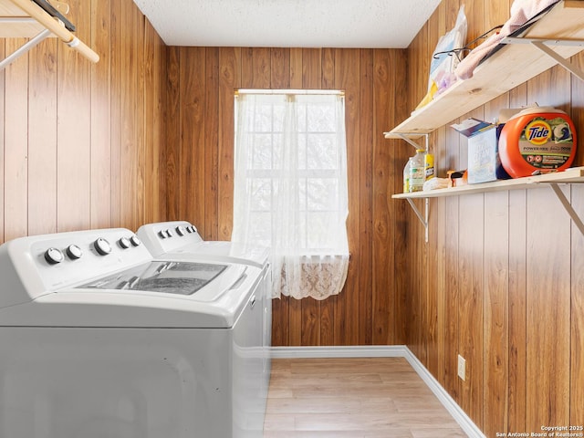 washroom featuring wooden walls, laundry area, a textured ceiling, wood finished floors, and washer and clothes dryer