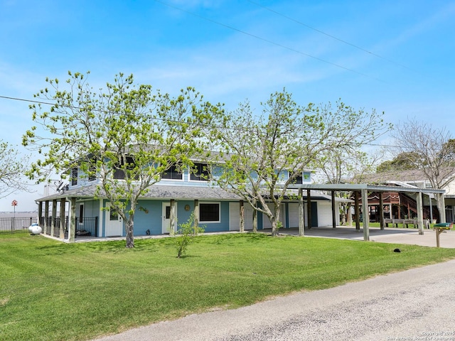 186 Trout, Palacios, TX 77465 - view of front facade with a front lawn, fence, a shingled roof, driveway, and a carport