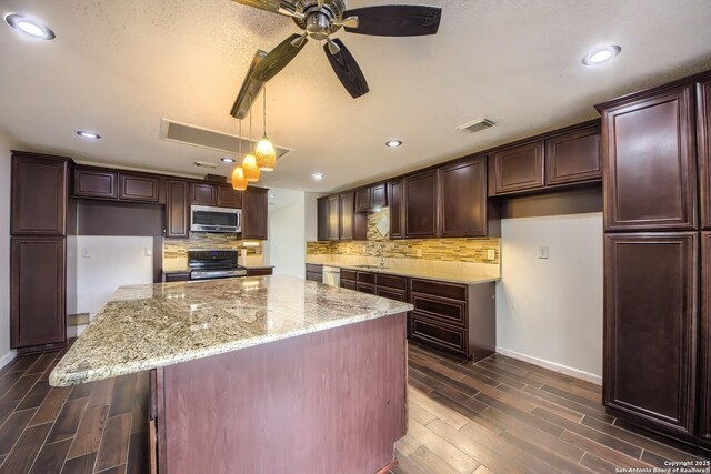 kitchen with stainless steel appliances, dark wood finished floors, decorative backsplash, and a sink