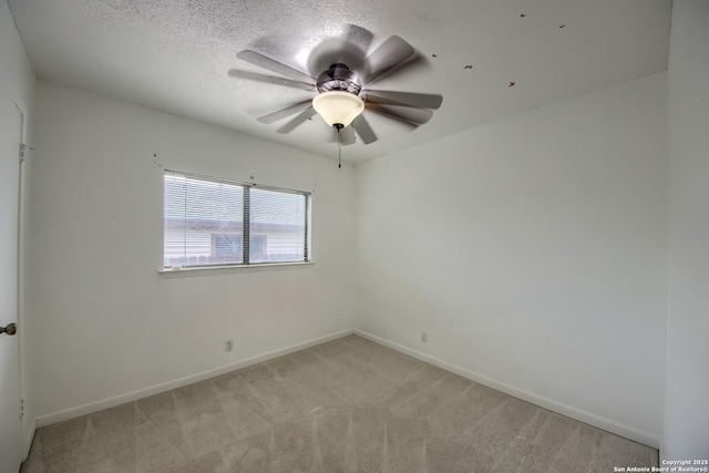 spare room featuring ceiling fan, light carpet, and baseboards