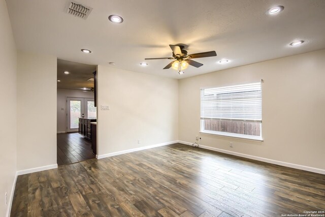 unfurnished room featuring visible vents, a ceiling fan, dark wood-style flooring, and baseboards