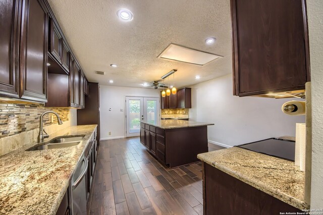 kitchen featuring dark wood-style flooring, a sink, a textured ceiling, baseboards, and backsplash