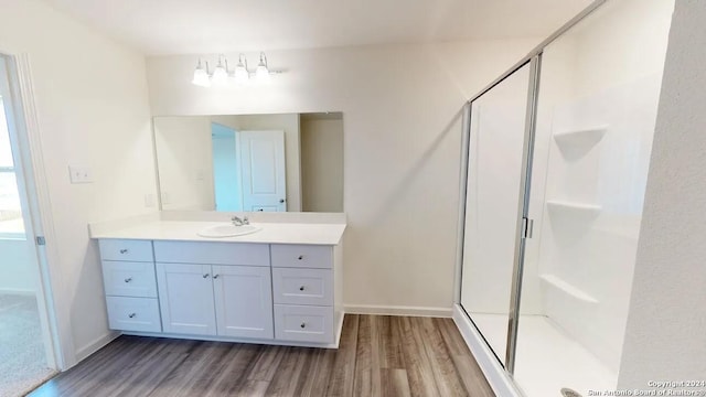 full bath with vanity, baseboards, wood finished floors, and a shower stall