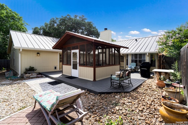 rear view of house featuring a standing seam roof, a chimney, metal roof, and a sunroom
