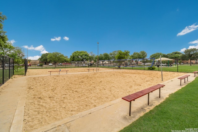 view of home's community featuring volleyball court, fence, and a lawn