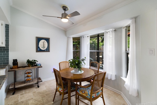 dining space with crown molding, baseboards, stone finish floor, a ceiling fan, and vaulted ceiling