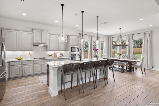3818 Cualquiera, San Antonio, TX 78261 - kitchen featuring stainless steel appliances, a sink, light wood-style flooring, light stone countertops, and decorative backsplash
