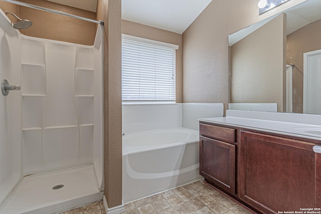 full bath featuring vanity, a textured wall, a bath, and a stall shower