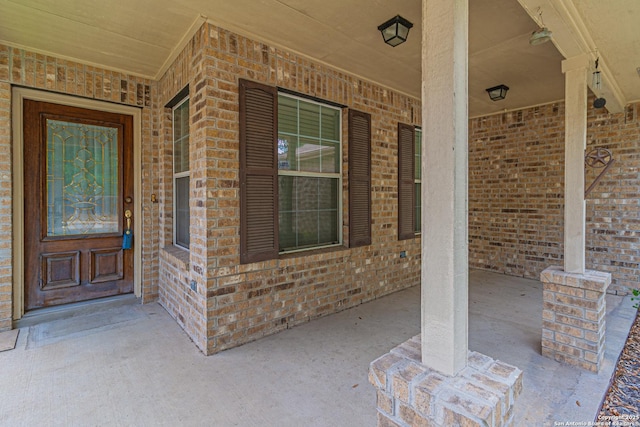 doorway to property featuring covered porch and brick siding