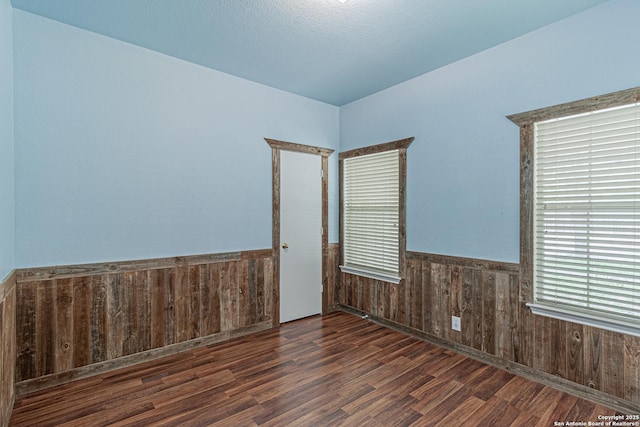 unfurnished room with wood walls, wainscoting, and wood finished floors