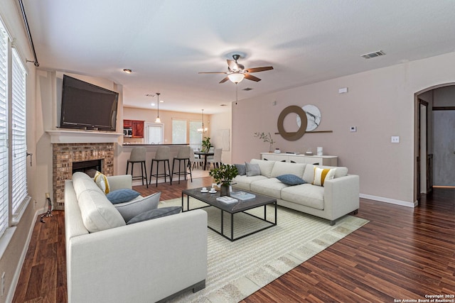 living area with visible vents, a fireplace, baseboards, arched walkways, and a ceiling fan