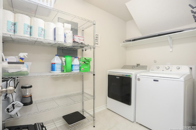 washroom featuring washing machine and clothes dryer, light tile patterned flooring, laundry area, and baseboards