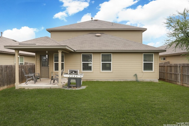 rear view of house featuring a patio, a fenced backyard, a lawn, and a shingled roof