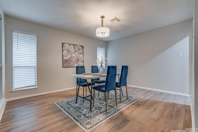 dining space featuring plenty of natural light, wood finished floors, and a notable chandelier