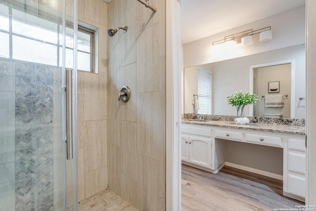 bathroom featuring a shower stall, wood finished floors, and vanity