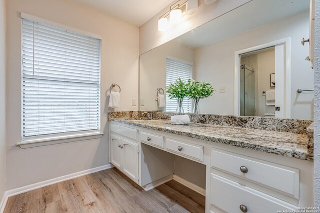 full bathroom with vanity, baseboards, an enclosed shower, and wood finished floors
